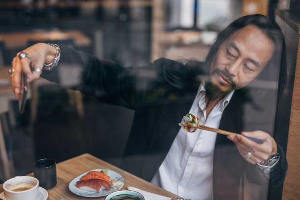 一名中国男子在餐厅吃寿司时自拍图片下载