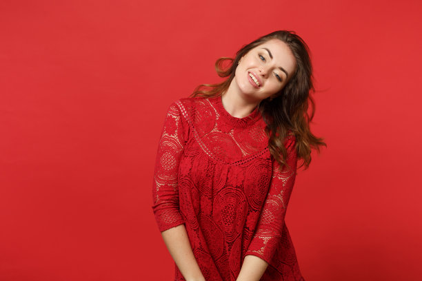 迷人的性感的年轻女人的肖像在蕾丝连衣裙站着和看相机孤立在明亮的红色墙壁背景在工作室。人真诚情感，生活理念。模拟拷贝空间。图片下载