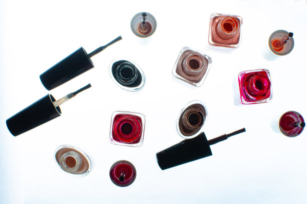 开过的瓶子，白色表面上涂着指甲油。俯视图图片下载