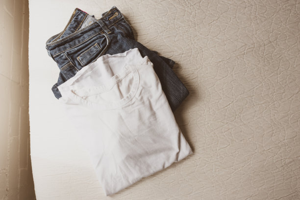 从上面看，白色t恤和蓝色牛仔裤放在床边上图片下载