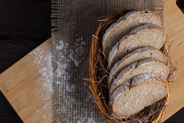 新鲜切成薄片的柳条碗放在橡木板上，上面撒有面粉，背景是亚麻织物。照片俯视图图片下载
