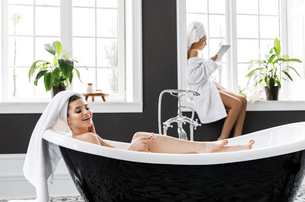 可爱的年轻女子穿着白色的睡袍，头上戴着毛巾在浴室里玩得很开心图片下载