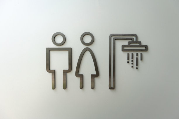 白墙上的厕所标志。男性和女性厕所图标制成的金属在黑色。图片下载