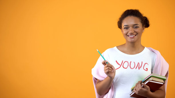 一个拿着书摆姿势拍照的少年，国际学生教育体系图片下载