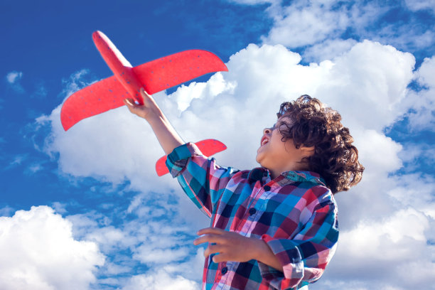 快乐的小男孩在户外玩红色的飞机图片下载