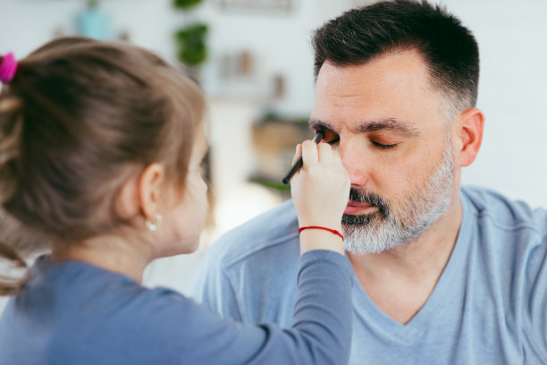 小女孩给爸爸化妆。图片下载