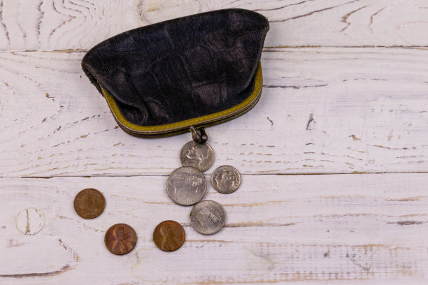 旧的零钱钱包与几枚硬币在白色木制背景。贫穷或破产的概念图片下载