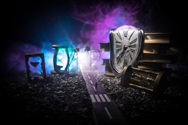 时间的概念。一个男人的剪影站在沙漏中间，在黑暗的背景上有烟雾和灯光。超现实主义的装修图片图片下载