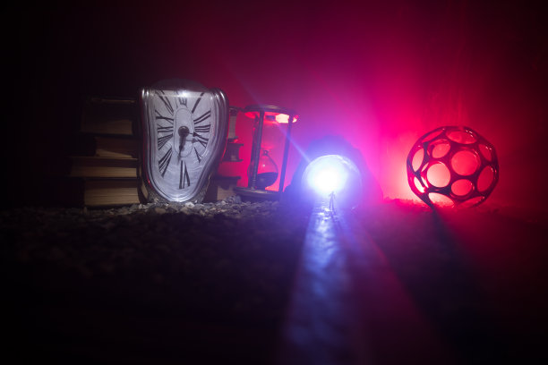 时间的概念。一个男人的剪影站在沙漏中间，在黑暗的背景上有烟雾和灯光。超现实主义的装修图片图片下载