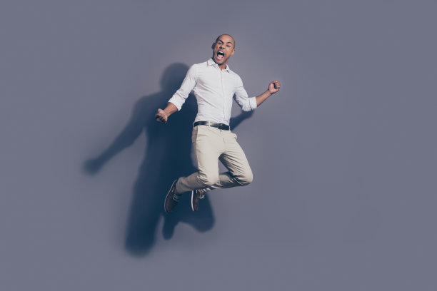 全身的身体尺寸照片惊人的大喊，大声，黑色的皮肤，他，他，他的男子气概，英俊的跳高，真正的球迷，啦啦队长，足球，棒球，篮球，穿白色的衬衫，蜡笔色的裤子，孤立的灰色背景图片下载