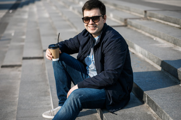 一个年轻人在城市里喝咖啡，然后走到外面。图片下载