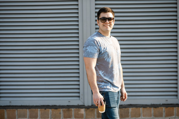 一个年轻人在城市里喝咖啡，然后走到外面。图片下载