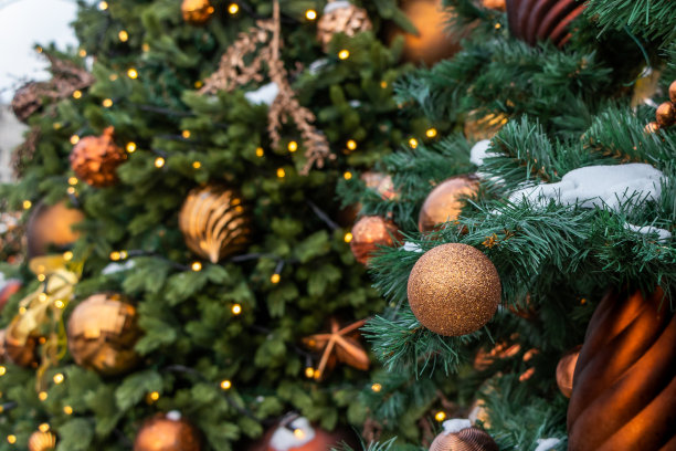 圣诞玩具挂满了雪的绿树上。金球特写，圣诞玩具和闪亮的球。圣诞节在街上，照片拍摄散焦图片下载