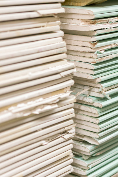 包装中的石膏板。准备施工的石膏板堆。在建筑仓库里装有石膏板的托盘。建筑材料。石膏板仓库。垂直的照片。图片下载