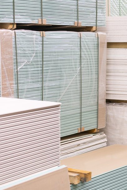 包装中的石膏板。准备施工的石膏板堆。在建筑仓库里装有石膏板的托盘。建筑材料。石膏板仓库。垂直图图片下载