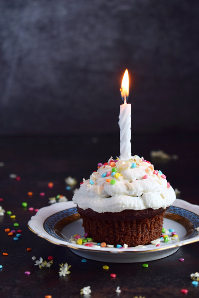 巧克力蛋糕加香草奶油和蜡烛。生日快乐。黑暗的照片。图片下载
