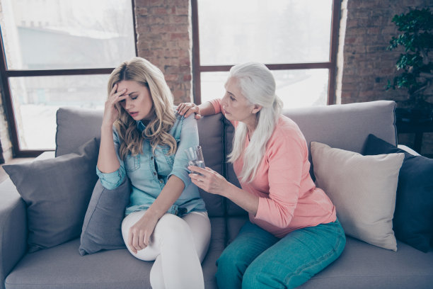 特写照片两个人，她，她的夫人，奶奶担心，带来水，想帮助，提供止痛药，握住，握住双手，手臂，玻璃，孙女，偏头痛，头痛，头痛坐在沙发沙发，沙发房子，室内图片下载