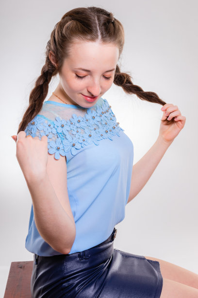 一个年轻女孩的肖像，低垂的眼睛拿着她的辫子图片下载