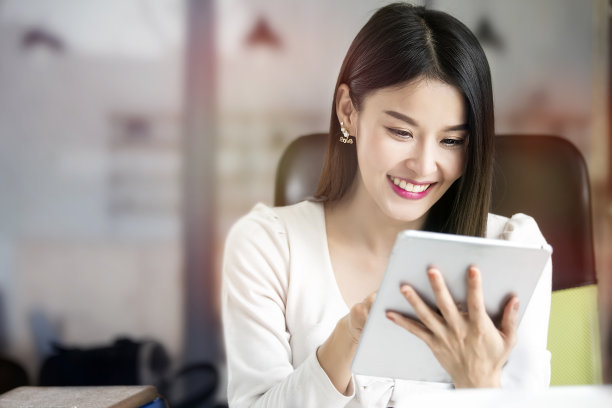 坐在办公桌前使用平板电脑的美女。图片下载