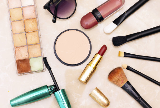 粉底粉和三色腮红，口红和睫毛刷和洗发水在粉色纸上图片下载