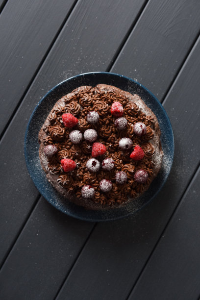 美味的巧克力蛋糕与巧克力糖霜和生浆果在黑色的背景图片下载