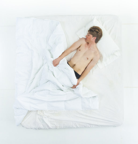 英俊的男人赤裸上身躺在床上图片下载