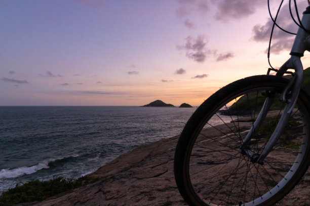 自行车轮子的背景是在巴西里约热内卢的海滩上的五颜六色的日落图片下载