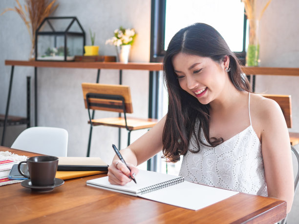 微笑的亚洲妇女用笔记本书写的室内图片图片下载