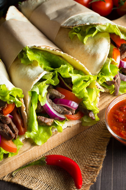 照片上的墨西哥三明治食物，玉米煎饼，菲希塔，玉米饼，玉米粉圆饼，牛肉，鸡肉，新鲜蔬菜在乡村的木制背景。快餐的概念。健康的午餐小吃。副本的空间。图片下载