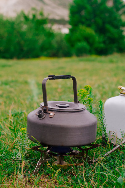 草地上的便携式露营煤气炉上的水壶图片下载