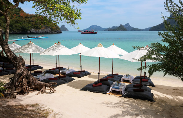 沙滩上挂着白色雨伞的豆袋，在热带岛屿上准备午餐图片下载