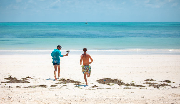 成熟的男人在沙滩上拍摄年轻的成年人图片下载