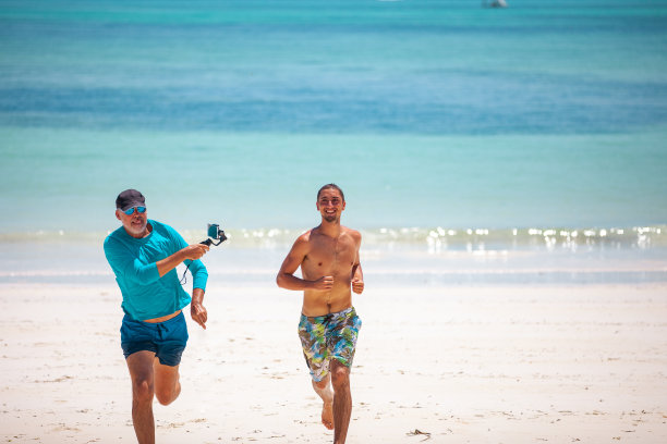 成熟的男人在沙滩上拍摄年轻的成年人图片下载