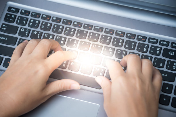 特写女子的手在笔记本电脑上打字图片下载