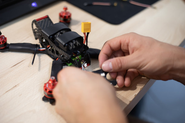 黑人安装和焊接赛车无人机在木桌上图片下载