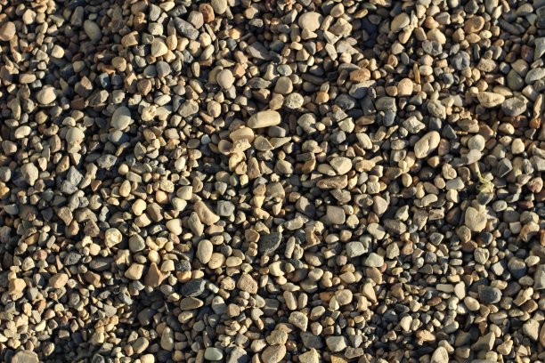 照片中的小灰棕色白色的石头在阳光的背景图片下载