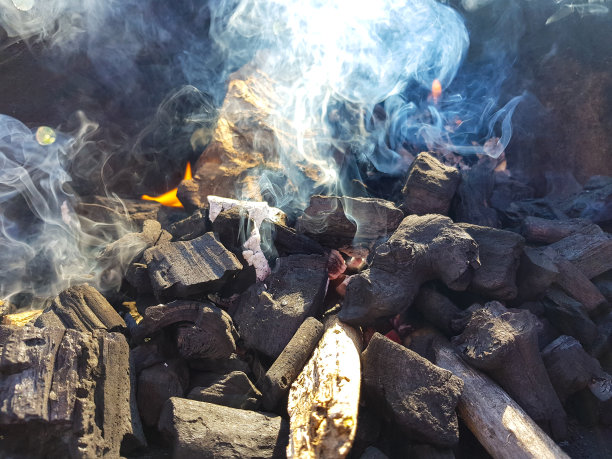 煤块在余烬上产生的烟。为烧烤余烬准备火。户外娱乐。图片中可以看到火焰。图片下载