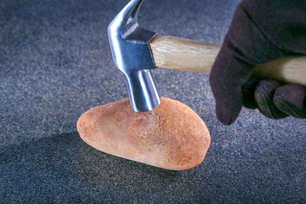 锤子敲击石头象征着稳定性测试。安全的概念图片下载