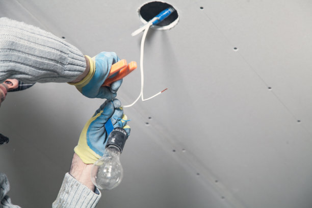 电工正在天花板上安装灯泡。图片下载