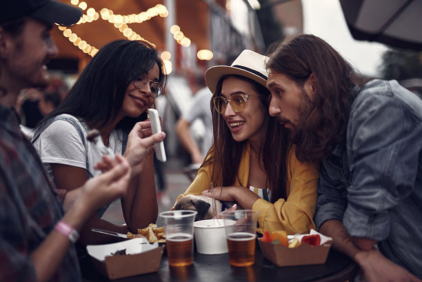 开心的朋友一边看智能手机，一边在户外咖啡馆消磨时间图片下载