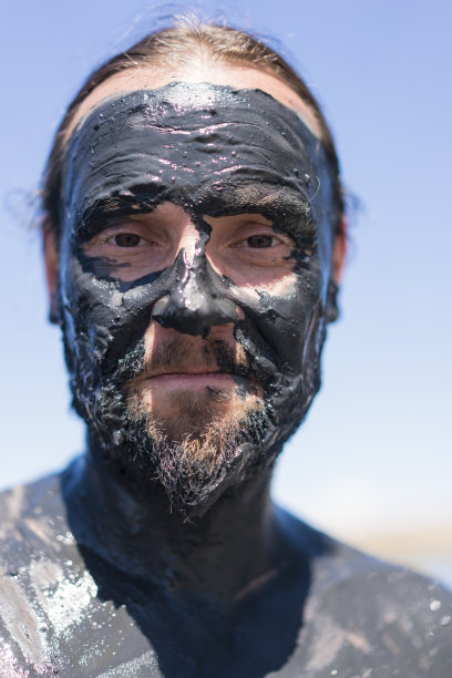 一名面带微笑的男子在伊塞克-库尔盐湖上，脸上覆盖着泥浆图片下载