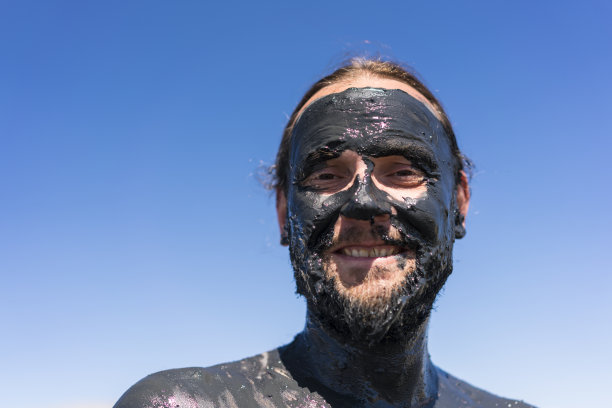 一名面带微笑的男子在伊塞克-库尔盐湖上，脸上覆盖着泥浆图片下载