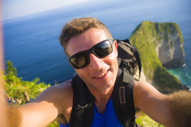 年轻的快乐和有吸引力的背包客男人用手机自拍照片在令人惊叹的海景前微笑愉快的感觉自由徒步在美丽的海滩悬崖图片下载