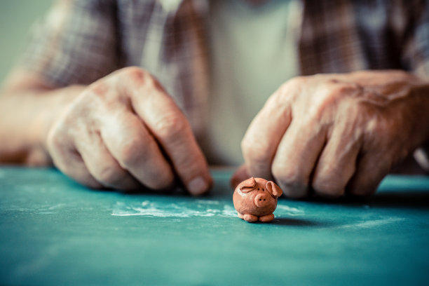 老男人的手和一只小泥猪站在前面图片下载