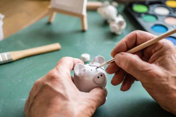 年长者双手近距离地画着小泥猪图片下载