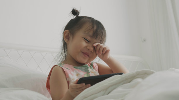 小可爱的泰国女孩使用智能手机(4岁)-股票图片图片下载