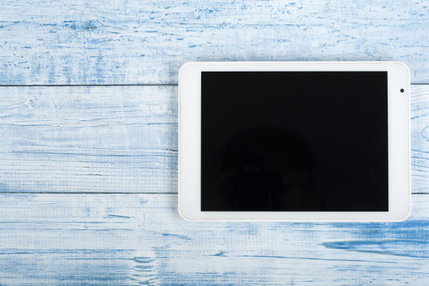 蓝色桌子上的数字平板电脑，办公桌。顶部视图与复制空间。图片下载