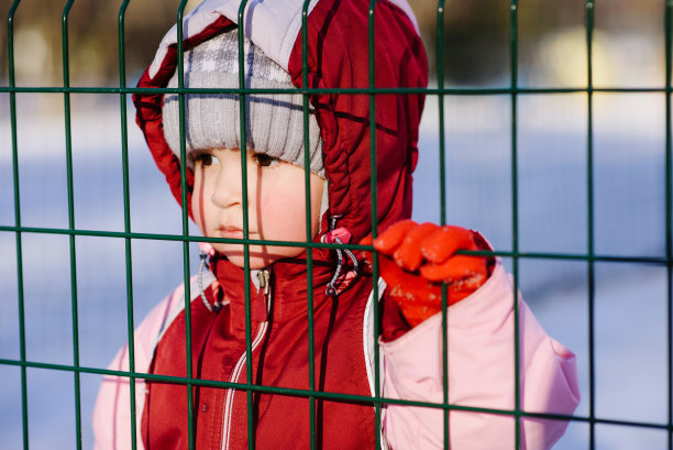 一个小孩透过栅栏看着，哭了图片下载
