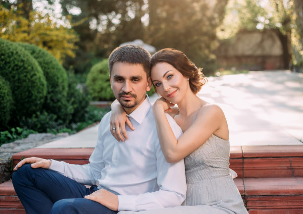 一对恩爱的夫妇在盛开的花园里拥抱。红头发的女孩穿着朴素的灰色乡村服装。时尚而低调的婚礼。飘逸的飘逸的发型。艺术照片图片下载