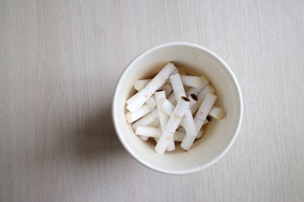 桌上的一个玻璃杯里装着烟头图片下载